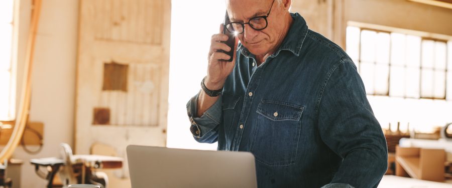 Man-on-phone-looking-at-laptop-Owner-Employee-Calculations-PPP-Loan-Forgiveness-KatzAbosch