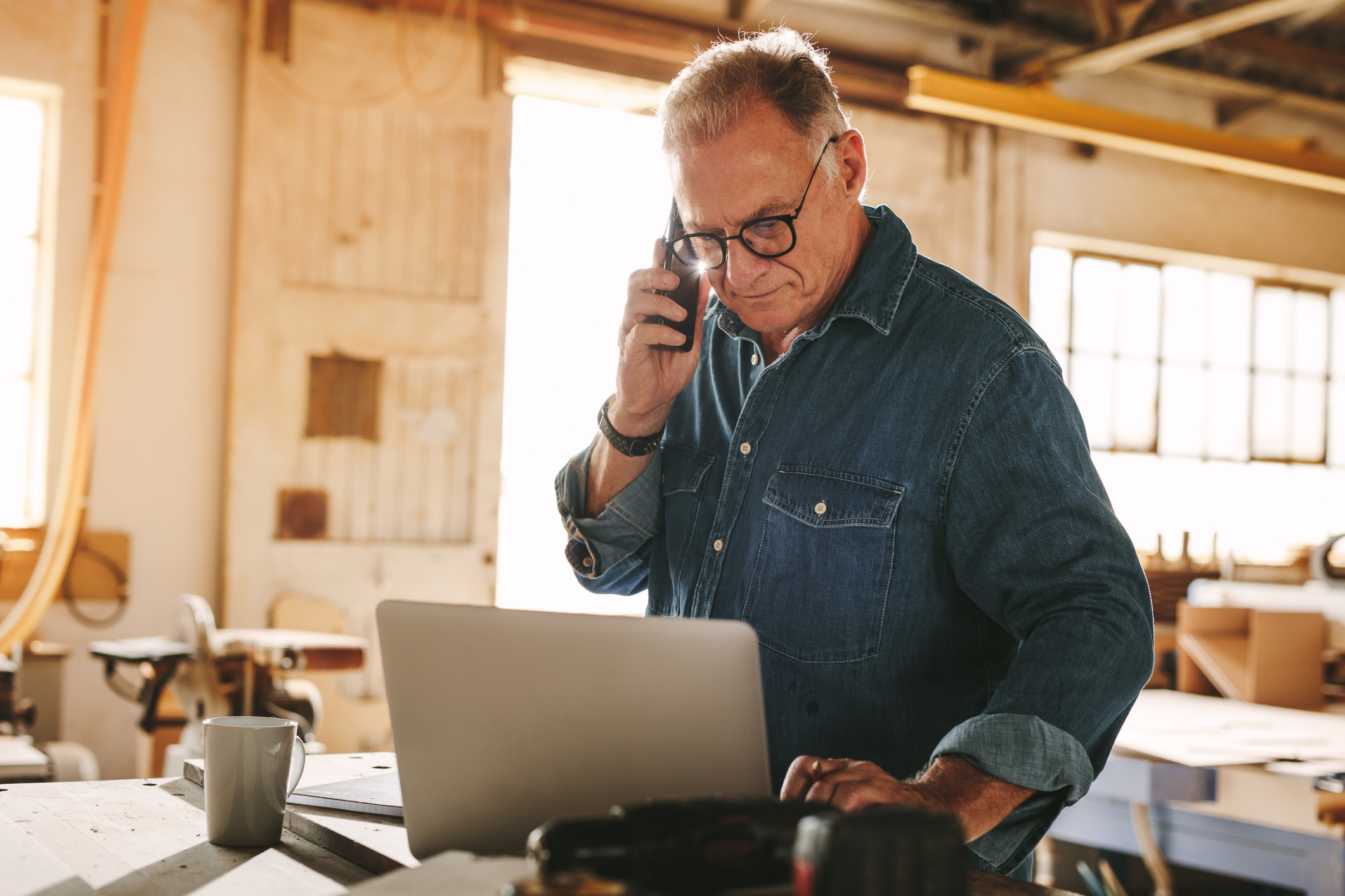 Man-on-phone-looking-at-laptop-Owner-Employee-Calculations-PPP-Loan-Forgiveness-KatzAbosch